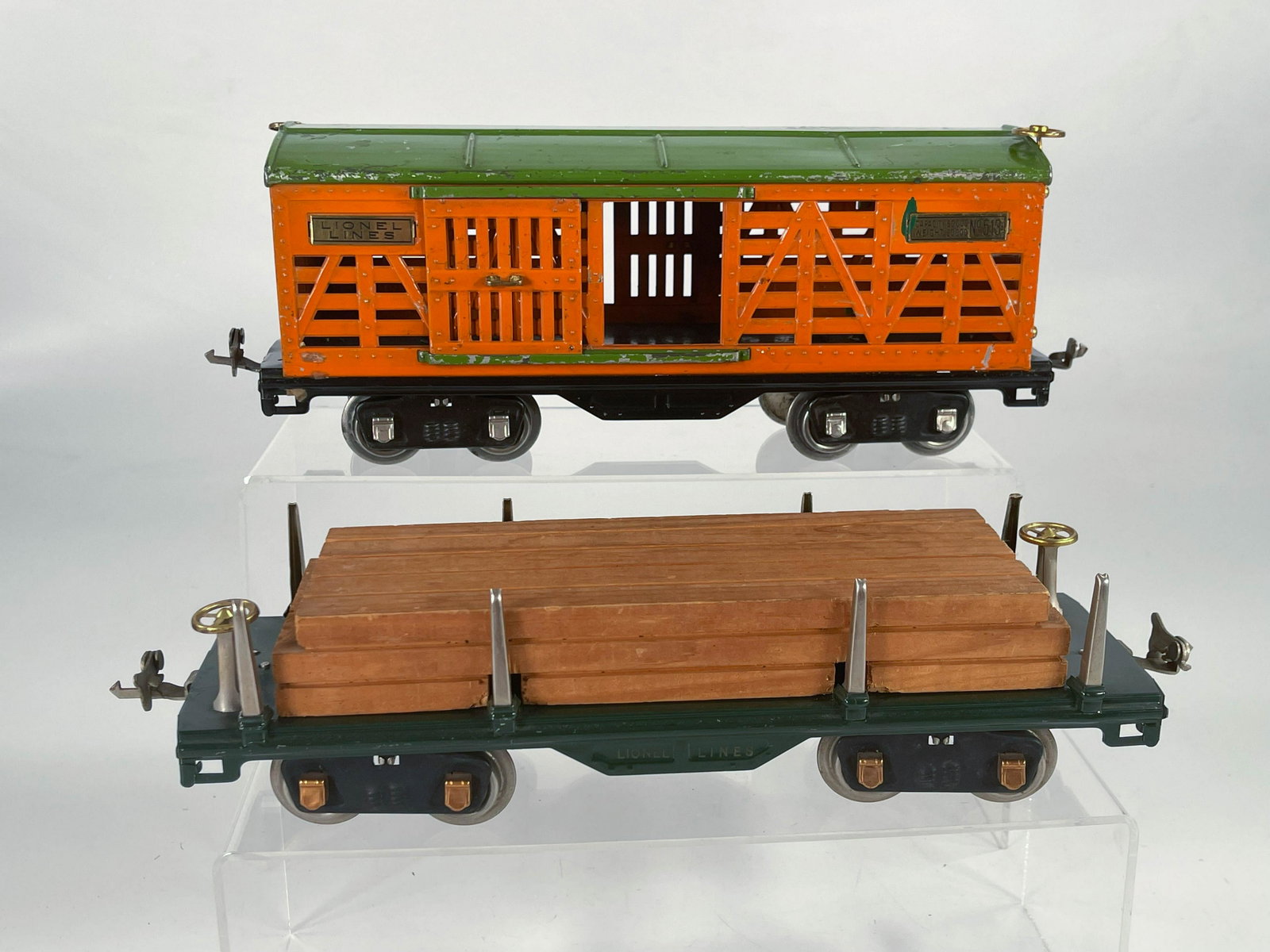 Lionel Prewar #513 orange/pea green roof live stock car: Lionel Prewar #513 orange/pea green roof live stock car and #511 dark green lumber car with load, with the #513 in C5 plus and the #511 in C7.