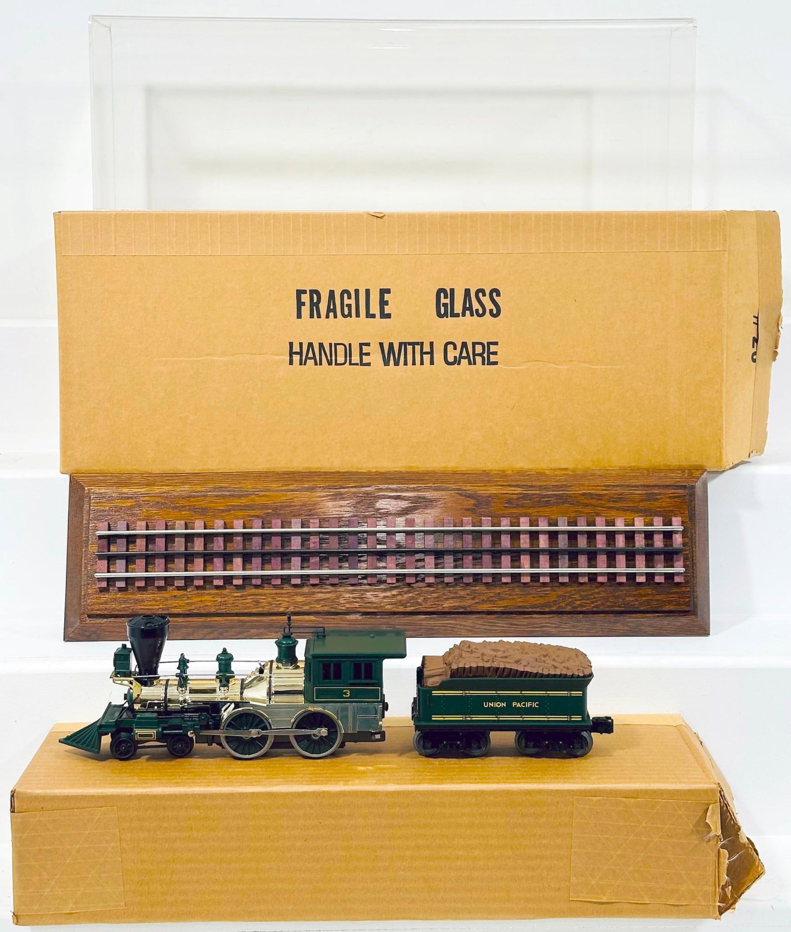 Lionel Modern O Gauge Union Pacific 4 - 4 - 0 Old Time Locomotive and Tender Boxed with Plexiglass: Lionel Modern O Gauge Union Pacific 4 - 4 - 0 Old Time Locomotive and Tender Boxed with Plexiglass Showcase, in C9 and with its original box and styrofoam packaging. This Lot also comes with a plexigl