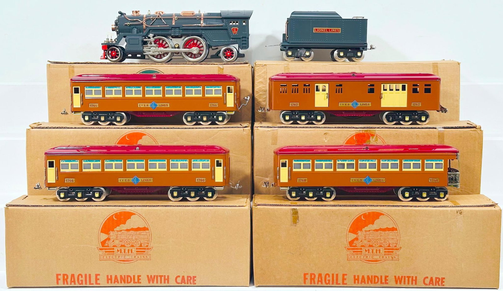 MTH Modern Standard Gauge 385 Gunmetal Locomotive and Tender and Four (4) Assorted Ives terra-cotta: MTH Modern Standard Gauge 385 Gunmetal Locomotive and Tender and Four (4) Assorted Ives terra-cotta maroon Passenger Cars, each in C8 or better and each with its original box.
