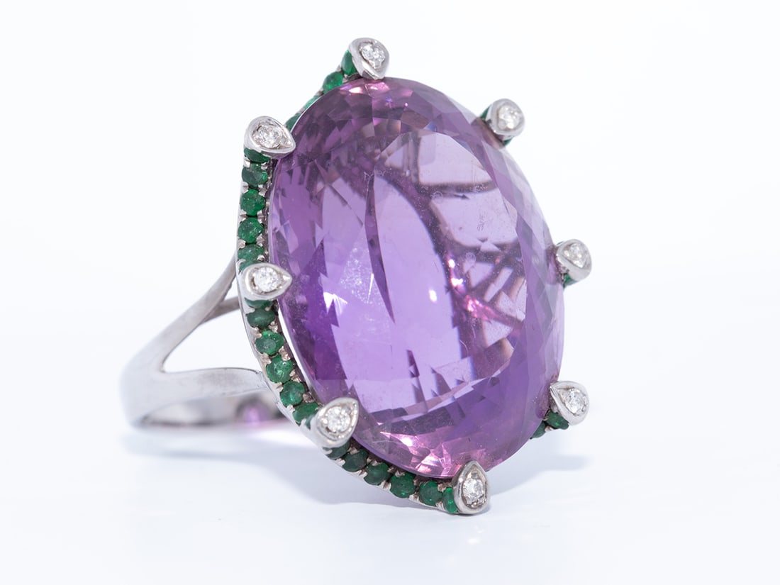 Big fashionable ring in white gold 18ct. with amethyst of 26cts. + emeralds and brilliants: Big fashionable ring in white gold 18ct. with 1 oval amethyst of 26cts. + 56 emeralds 0.56ct. and 16 brilliants 0.30ct. color: F and clarity: VS dim. ring: 30 x 24 mm. size: 54-57