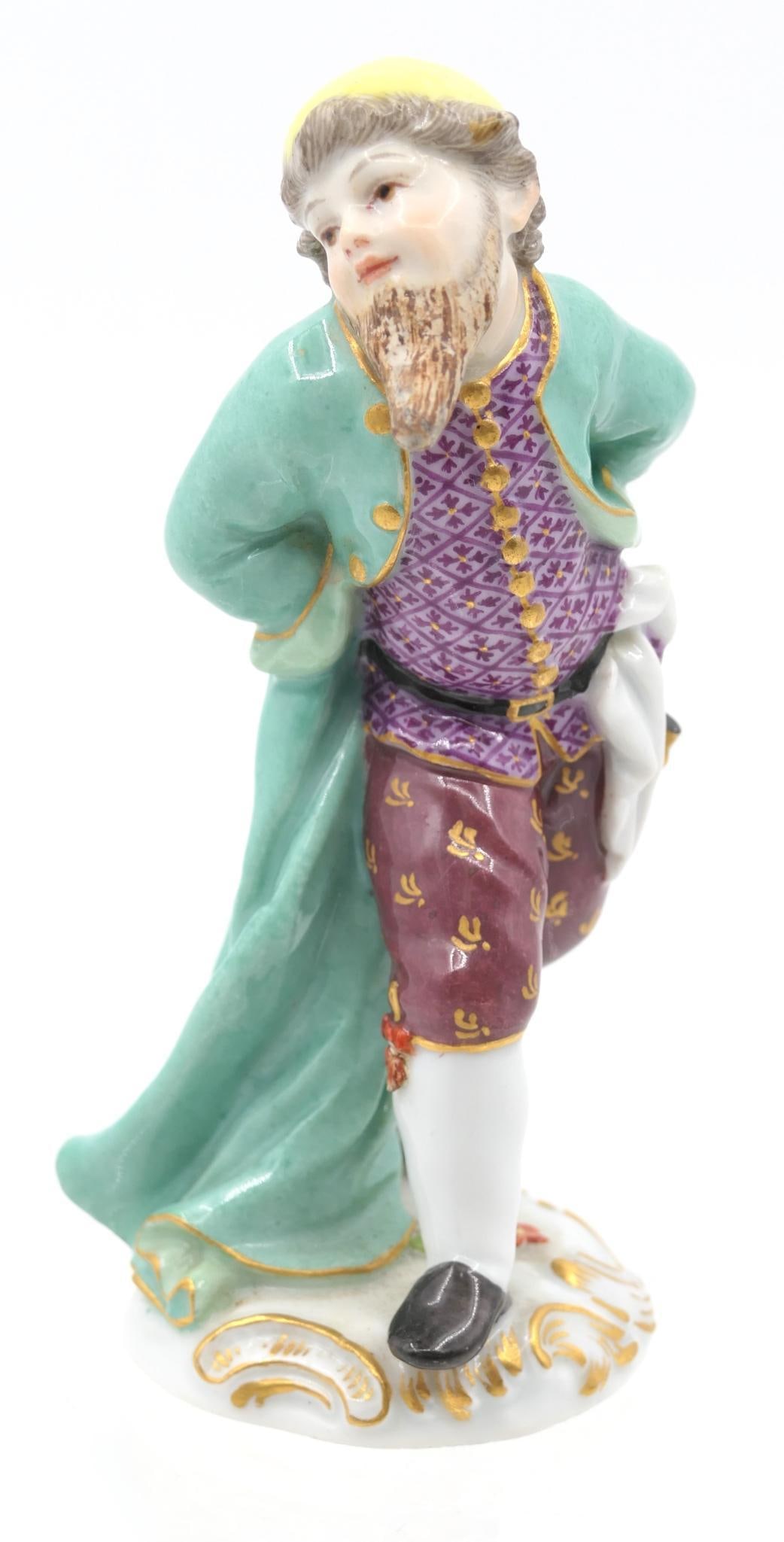Meissen Man with Blue Coat Figurine: Porcelain figurine depicting a man in a blue coat and yellow cap, featuring gilt accents throughout. Marked with the double sword marking on the base, with incised numbers "11a" and "107". Beard area 
