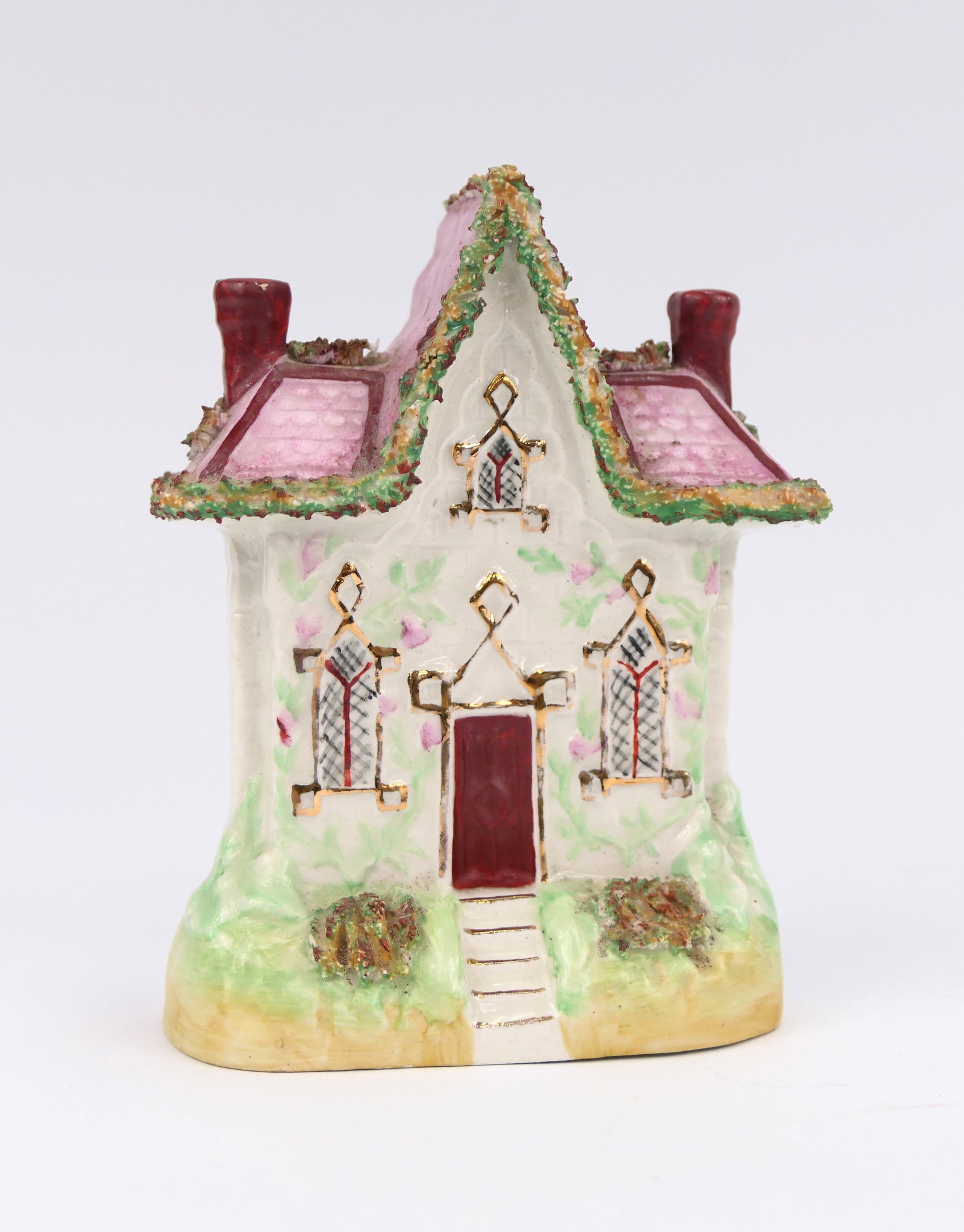 Antique Staffordshire Pearlware Coin Bank: Circa 19th century porcelain coin bank by Staffordshire England, featuring a cottage design with pink pearlware finish and floral accenting. The slot is located on the back, with no stopper for coin r