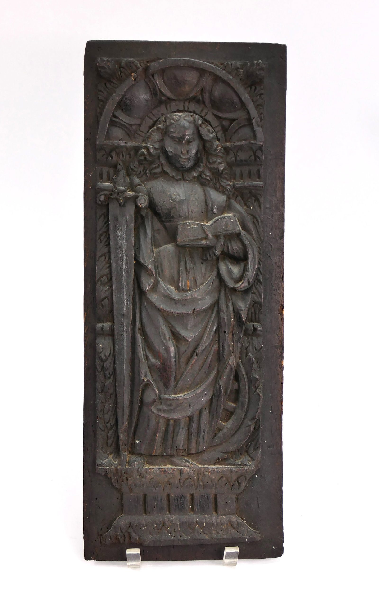 Wooden Relief Carving: Wooden wall hanging relief carving depicting a woman in a frilled collar holding a book and an imposing broadsword, accented by archway and columnar motifs. Size: 7.75"w x 19.75"h