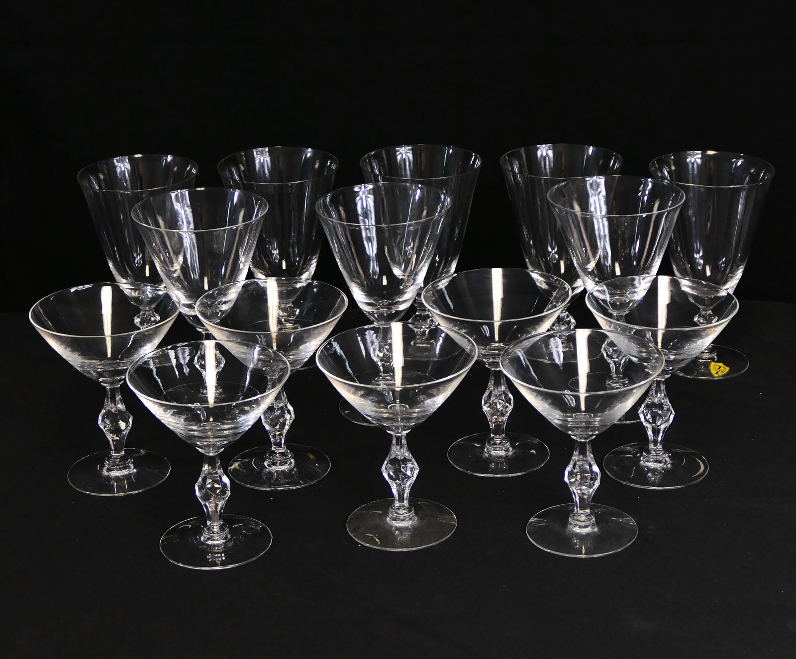 Tiffin Crystal Stemware Assortment: Assortment of Tiffin Crystal stemware featuring faceted accent stems, including three wine glasses, five tea goblets, and seven champagne or tall sherbet glasses. One is marked with a sticker. Size: 6
