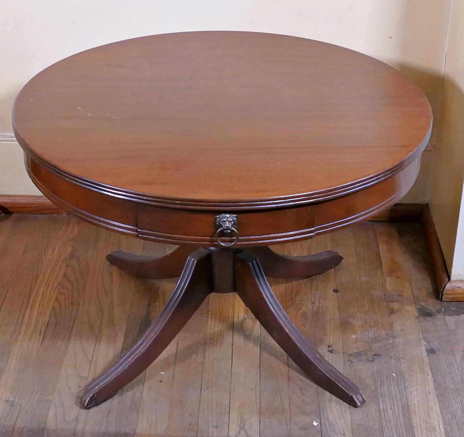 Vintage Mahogany Coffee Table: Circa 1940's mahogany finish Duncan Phyfe single drawer coffee table on quatrefoil incised line legs. Upper surface shows scratches from regular use. Size: 28"dia x 19"h Location: Library