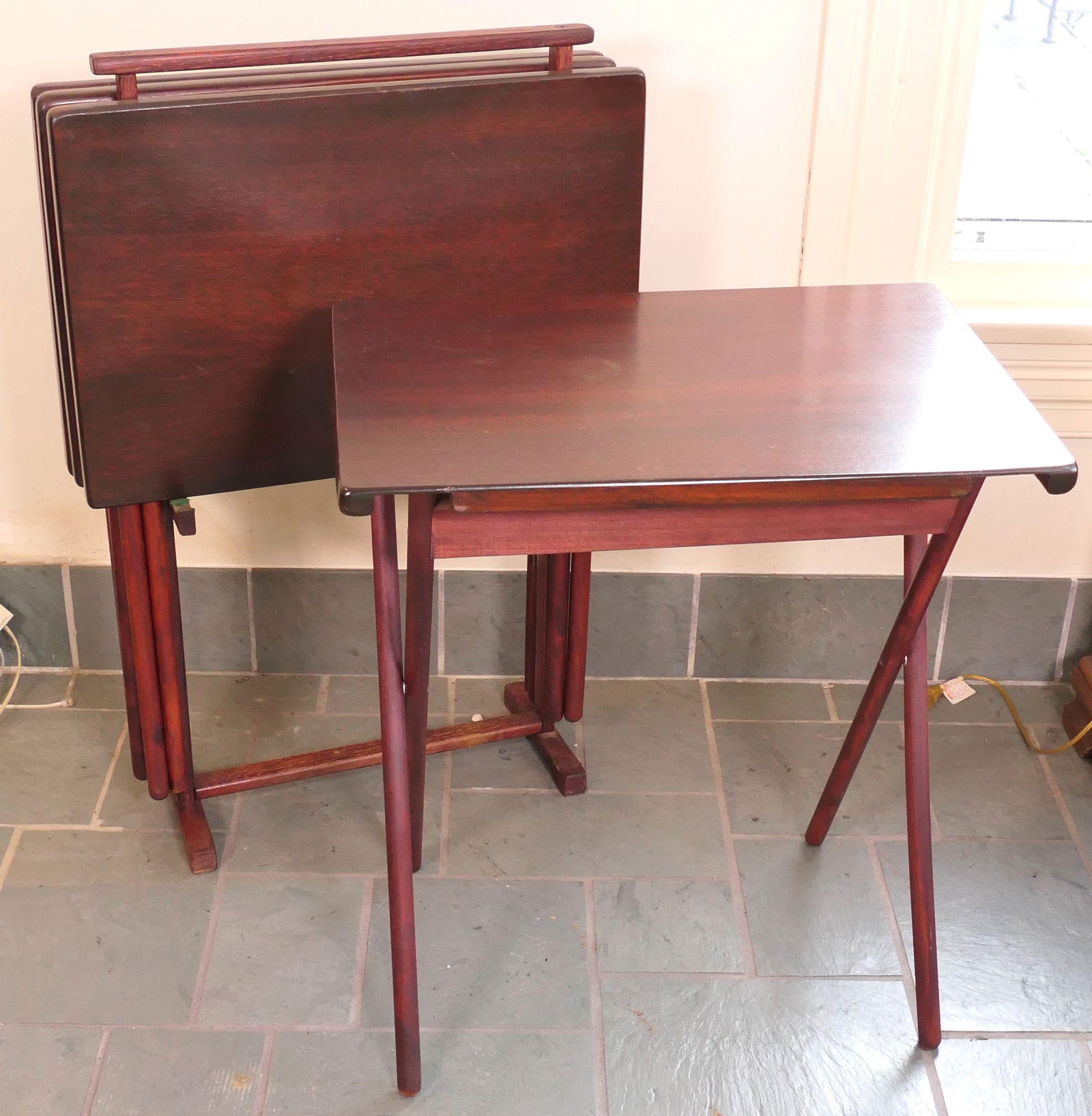 Set of Mahogany Tray Tables: Set of (4) mahogany tray tables resting on single handle with trestle legs. Size: 30"h Location: Sunroom