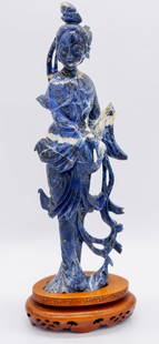 Hand Carved Blue and White Veined Sodalite Geisha: Hand carved blue and white veined sodalite geisha adhered to hand carved oval wood base. Broken piece of sodalite included for repair. Size: 11&rdquo;h with base Location: Sitting Room