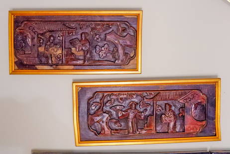 Pair Of  Chinese Carved Wood Panels: Two finely carved Chinese wood panels, each depicting detailed figural scenes. The carvings are mounted in complementary gold-toned frames. Each features a narrative scene with traditional architectur
