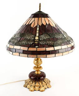 Tiffany Style Lamp: Tiffany style dragonfly themed faux leaded glass lamp with single socket, gilded metal lamp post with foliate and bell flower shape pierced design. There is a bohemian red cut to clear circumference g