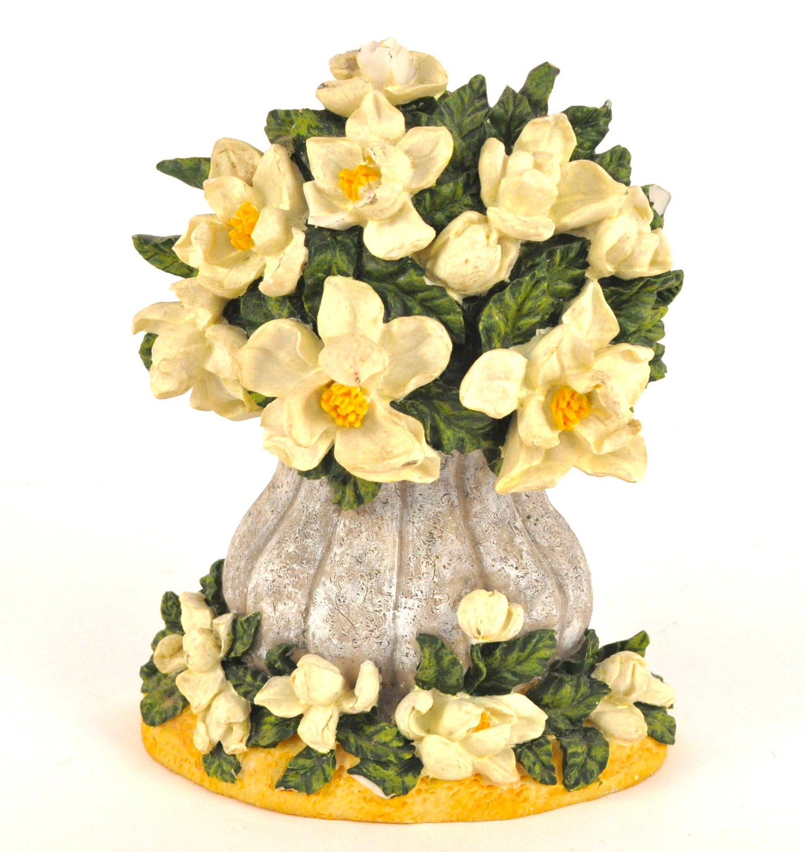 Plaster Floral Doorstop: Plaster doorstop in the form of a textured grey urn overflowing with blooming magnolia-style cream color flowers and lush green foliage on yellow base. Size: 8.5"h Location: Primary Closet