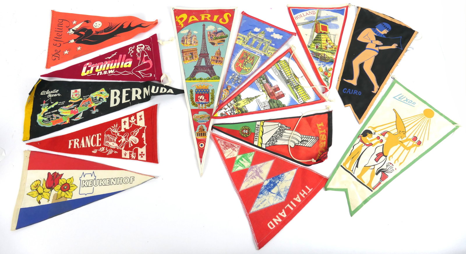 Thirteen Vintage Travel Pennants: Thirteen vintage international travel pennants in felt, vinyl and other materials. Representing Paris, Thailand, Norway and more, some are 2 sided. Size: Paris 17"w x 6.5"h