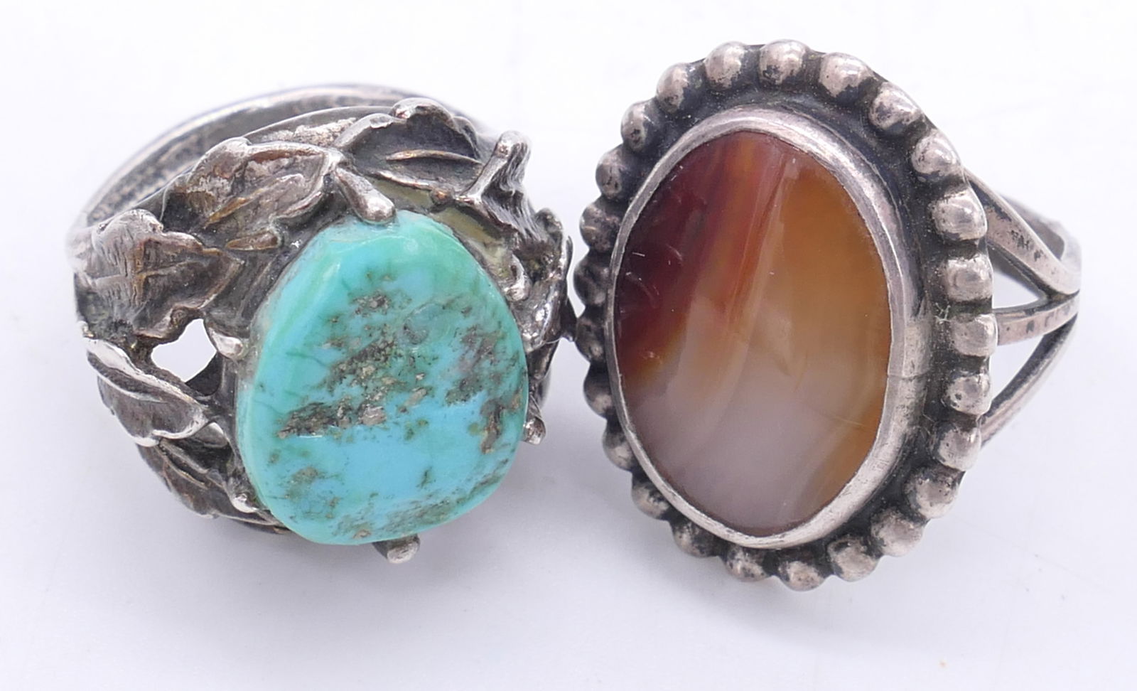 Two Sterling Rings: Two sterling rings including one featuring an orange agate (size 7) and one with a leaf design surrounding a turquoise center stone (size 6). Total weight: .465 ozt