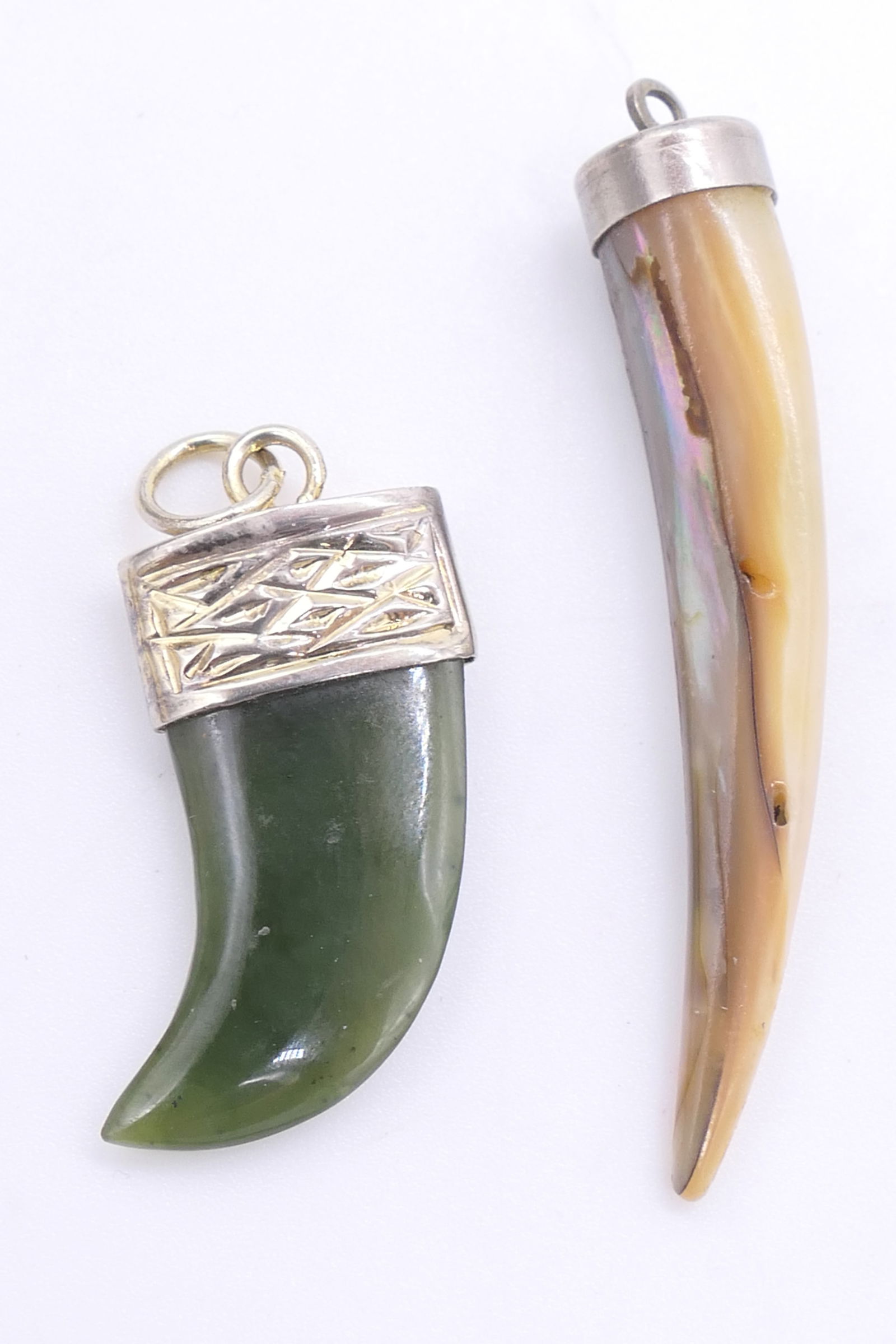 Two Fang Shaped Stone Pendants: Two fang shaped stone pendants including nephrite jade with top marked M silver and mother of pearl. Size: Largest 1.5"h