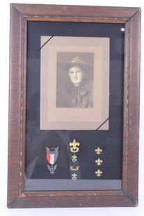 Boy Scout Memorabilia: Boy Scout memorabilia including photo of scout in uniform, Eagle Scout medal and other pins. All displayed in oak framed shadow box. Some damage to frame and wear from age. Size: 18"w w x 23.5"h