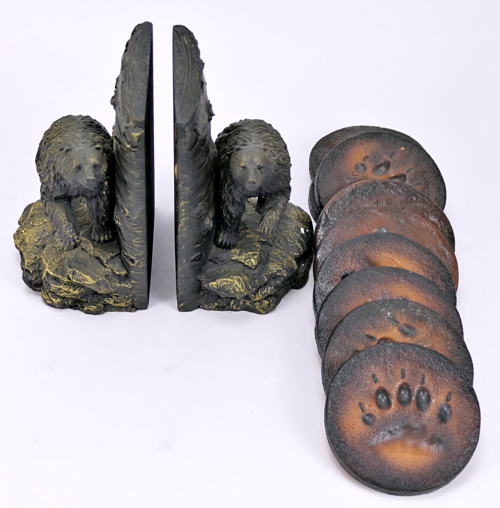 Bear Themed Bookends with Bear Paw Print Coasters: Pair of bear themed bookends and set of stylized bear paw print coasters. The bookends are made from plaster and have a gold wash. One is chipped. Size: Bookends 5"w x 4"d x 7"h