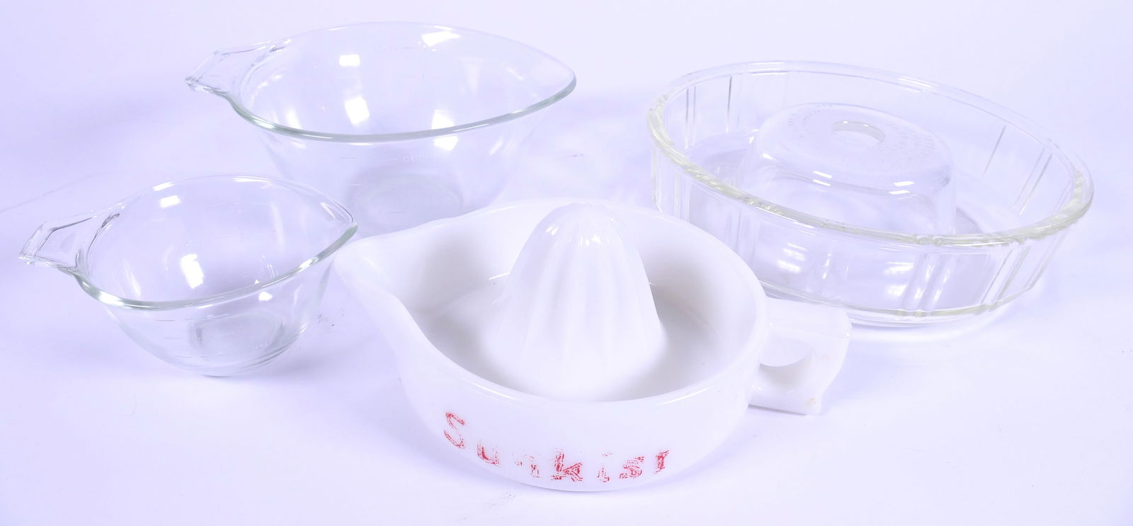 Vintage Glass Kitchenware: Vintage glass kitchenware including 1940's Queen Anne Glasbake mold, 1950's Sunkist milk glass juicer (color loss) and (2) Pyrex measuring bowls. Size: Largest 8.75"dia x 1.5"h Location: Kitchen