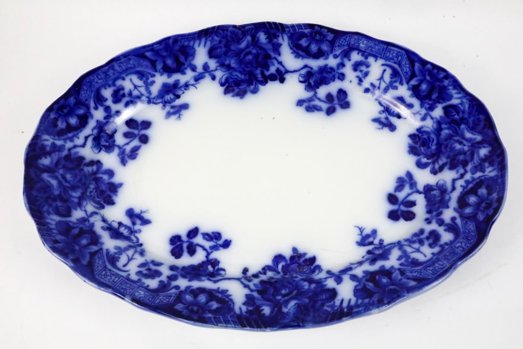 Flow Blue Hollinshead & Kirkham Tunstall Platter: Flow blue platter in the "Togo" pattern by Hollinshead and Kirkham (England), Earthenware with unicorn mark. Floral vines surrounded the wavy edges, leaving a clear white center. Size: 16"w x 11.75"d