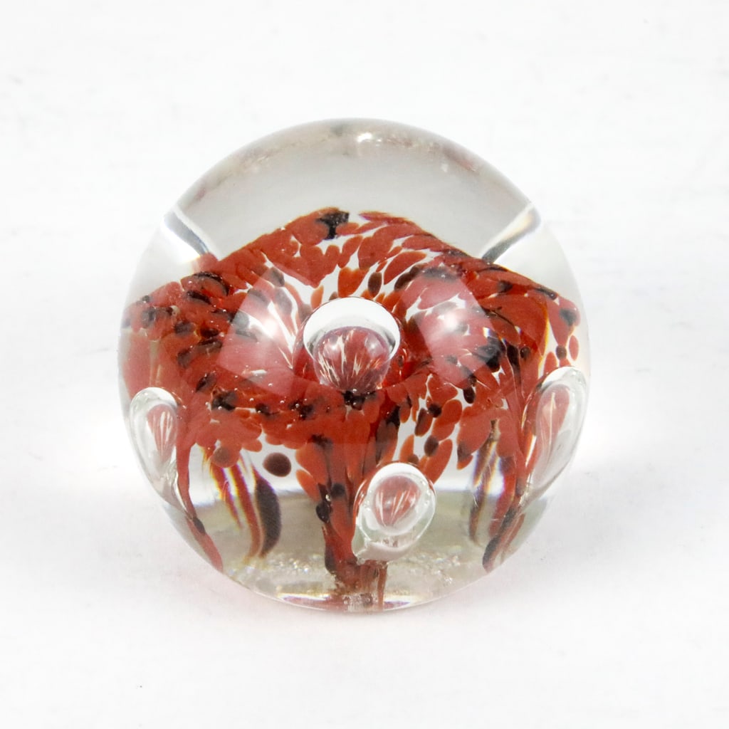 Kerry Zimmerman Signed 1986 Paperweight: Kerry Zimmerman signed 1986 paperweight with red and black flecks and controlled bubbles. Etched around the bottom center with the date 86'. Size: 2"dia