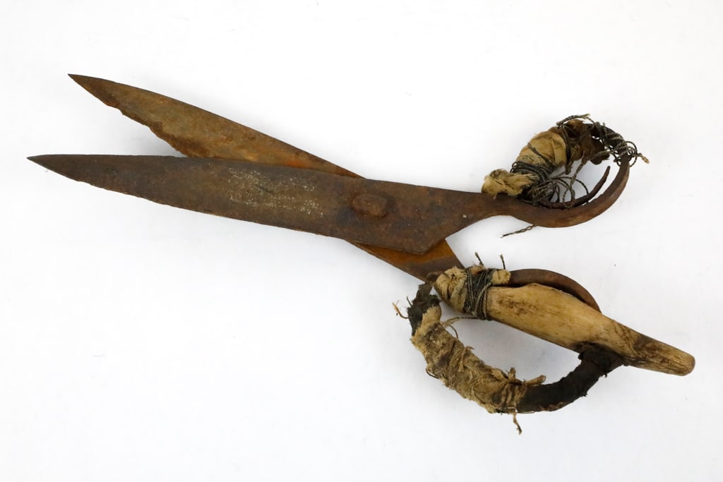 Antique Colonial-Era Iron Shears: Antique Colonial-era iron shears with a spring handle style blade. The blade displays heavy surface wear, oxidation, and age-darkened patina. There are fabric remnants and hand-tied wire likely served