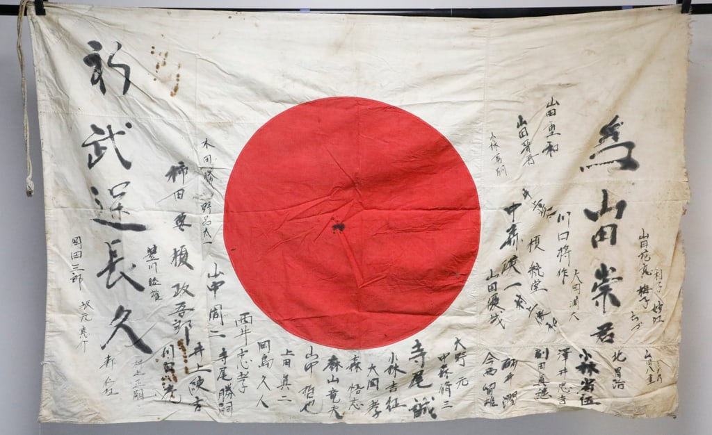 World War II Era Japanese Flag: World War II Era Japanese flag, known as a good luck flag (Yosegaki Hinomaru). These flags were carried by soldiers as personal talismans for protection. Typically made of cotton, with drawstring styl