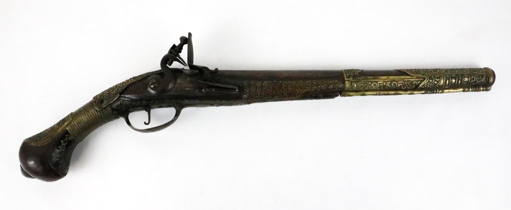 Engraved European Flintlock Pistol: Engraved European flintlock pistol with decorative brass fittings on the barrel, wrist and grip- featuring a .64 caliber. The scroll engraved lock is marked, "M.Delince". There is inlaid brass fitting