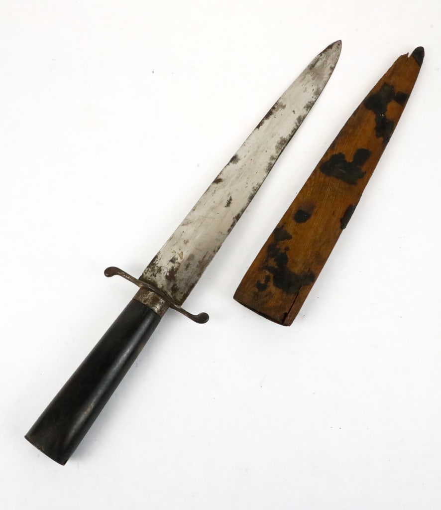 Double Edge Dagger with Brass Guard: Double edge dagger with brass guard and bone like handle. The blade edges are dull, and the dagger is very symmetrical in appearance. The scabbard is a homemade wooden holder with damage to the point
