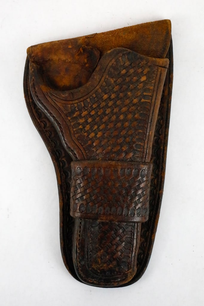 Leather Gun Holster: Leather gun holster with basket weave design that fits a loop on the front. The holster shows no belt loops in a western style, possibly made A.W. Britt in Austin, Texas. The holster is designed to ca