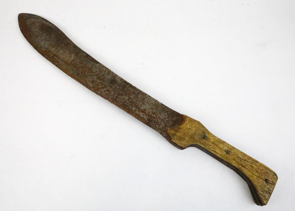 Heavy Machete with Hand-Forged Double-Edged Blade: Heavy machete with hand-forged thick, double-edged blade with bone handle. The blade show history of usage maintaining a dull blade. Minor crack around rivet on handle and rust present on blade. Size: