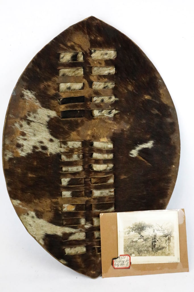 Hide Shield with Woven Sections, Possibly South African Zulu: Shield with two woven sections, possibly cow hide. Includes vintage photograph of man in traditional dress holding shield, possibly South African Zulu. Size: 14.5"w x 20.25"h