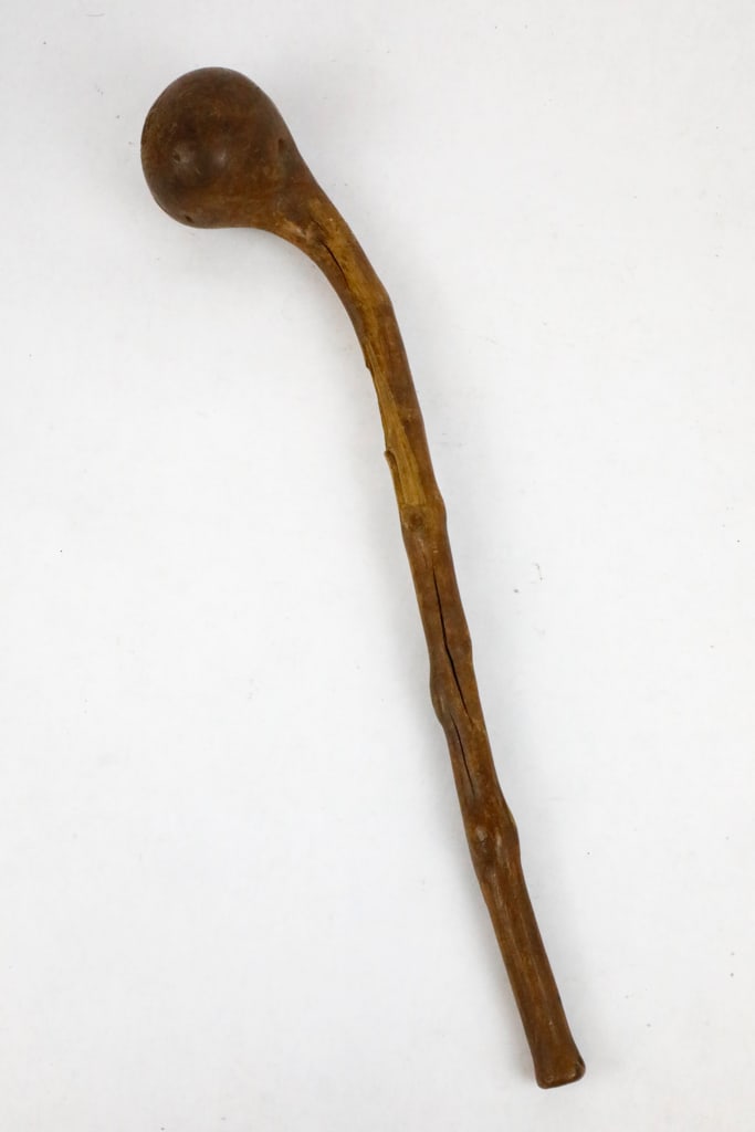 Carved Wooden Hand Club: Wooden hand club, that features a short staff and smooth bulbous end that has two holes drilled into it, potentially used to attach a strap or be decorative. The club is short, so it was most likely u
