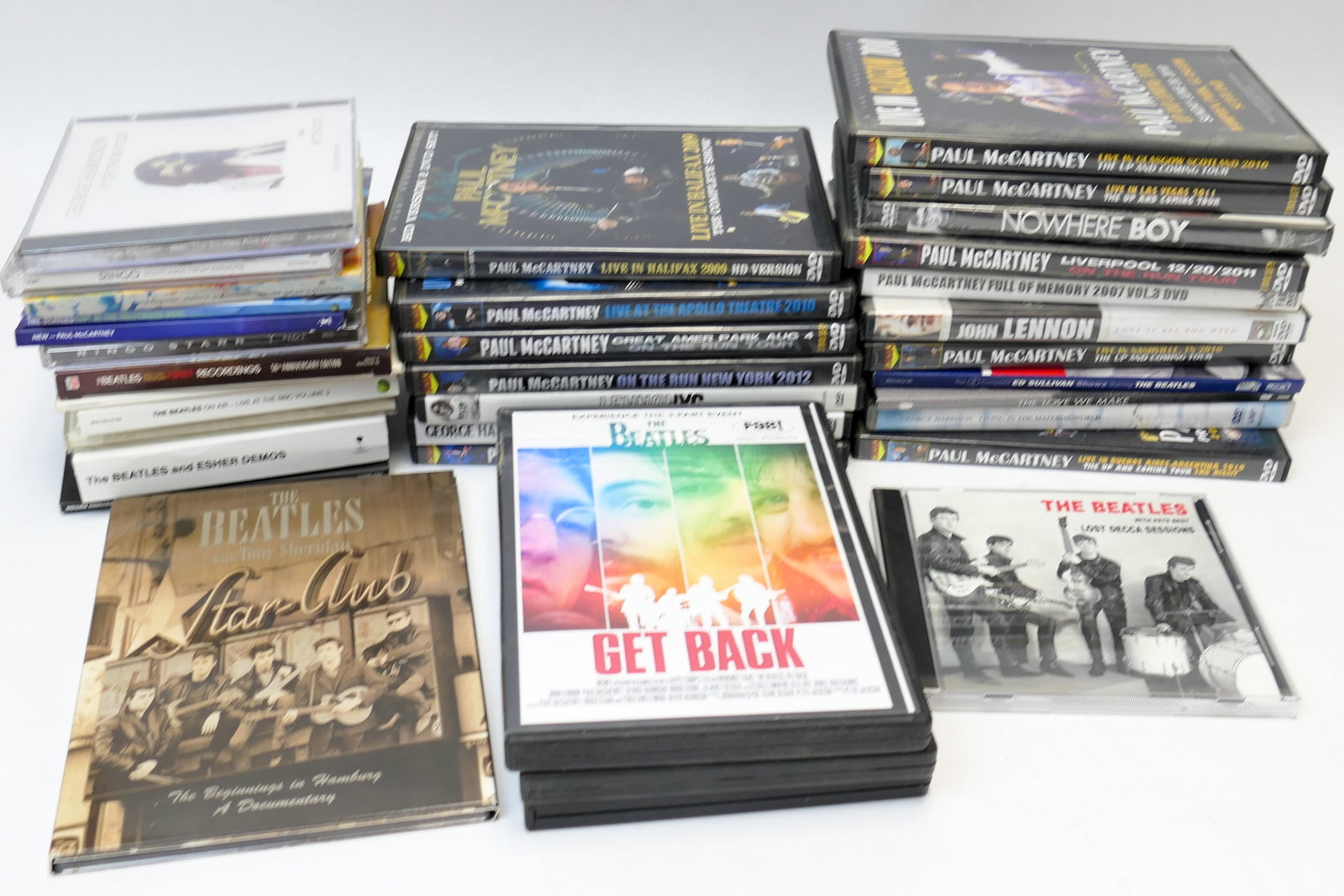 Collection of Beatles CDs and DVDs: Collection of Beatles CDs and DVDs including titles such as Nowhere Boys, Paul McCartney Live At The Apollo Theater 2010, George Harrison Archives 2001, The Love We Make, Beatles Ed Sullivan shows, Jo