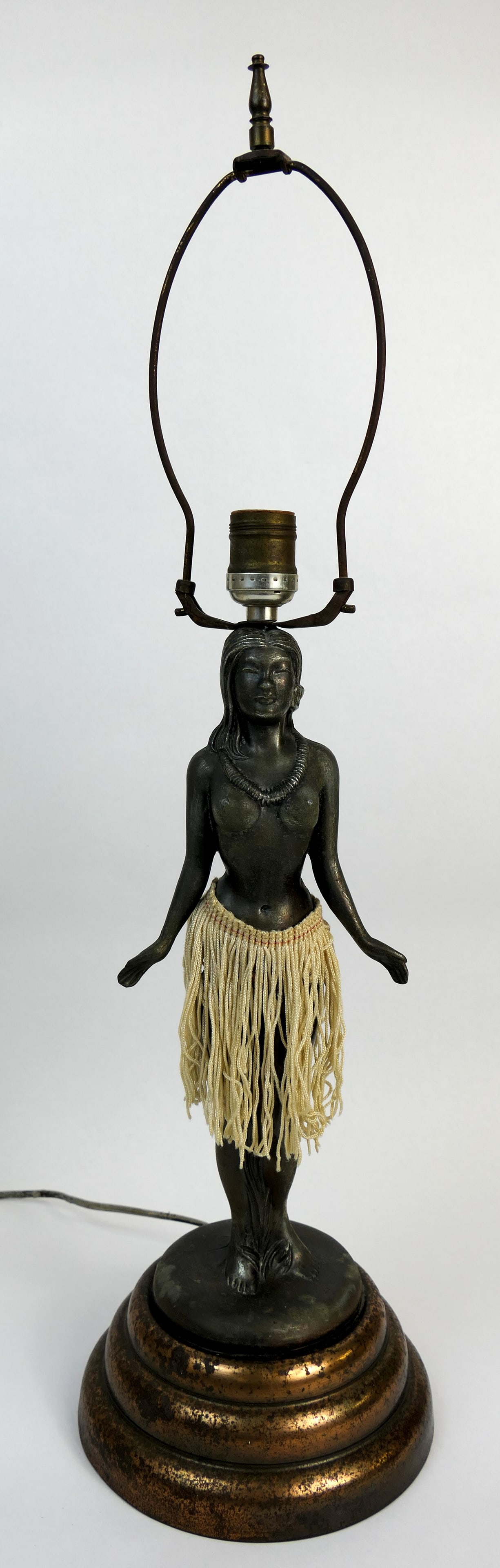 Metal Tropical Hula Lamp: Tropical hula lady lamp, featuring a graduated copper tone base and a metal figural statue post with a fiber tassel skirt, and a single socket rising from her head The hips of this topless figure cont