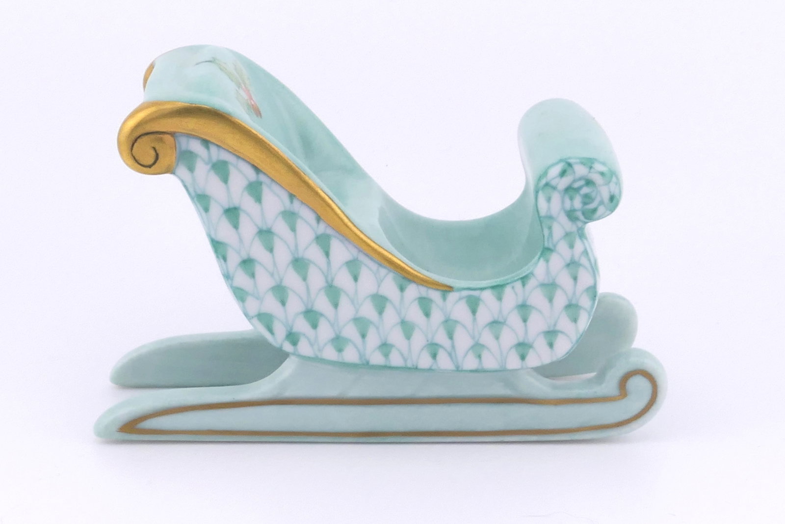 Herend Sleigh Figurine: Marked Herend porcelain figurine featuring a sleigh design in lime green fishnet patterning. Marked on the bottom Herend, Hungary. Excellent condition. Size: 1" w x 3.25"d x 2"h Location: Living Room
