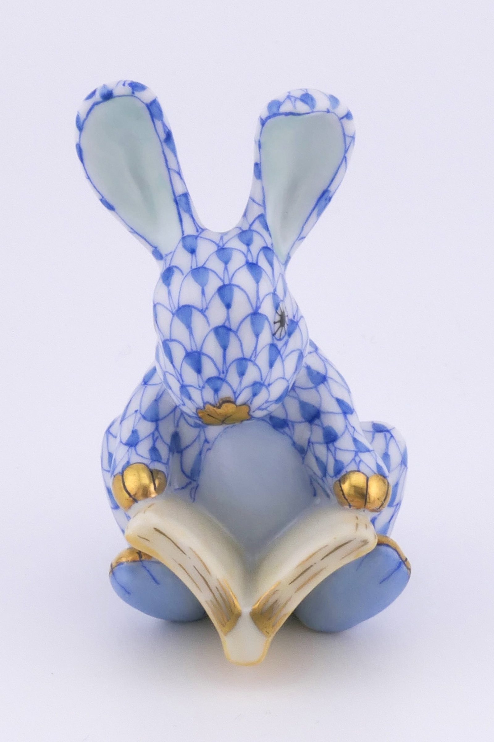 Herend Reading Rabbit Figurine: Marked Herend porcelain figurine featuring a rabbit design holding a book in blue fishnet patterning. Marked on the bottom with the Herend insignia. Excellent condition. Size: 1.25"w x 1.75"d x 2.5"h