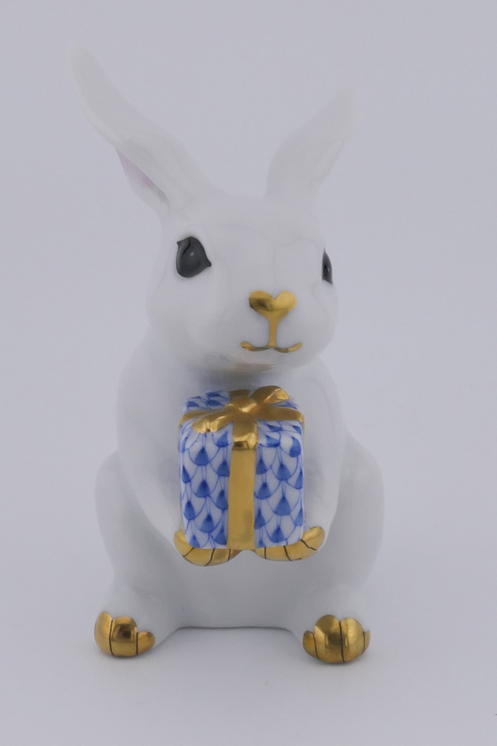 Herend Celebration Rabbit Figurine: Marked Herend porcelain figurine featuring a celebration rabbit design holding a blue fishnet patterned present. Marked on the bottom with the Herend insignia. Excellent condition. Size: 1.5"w x