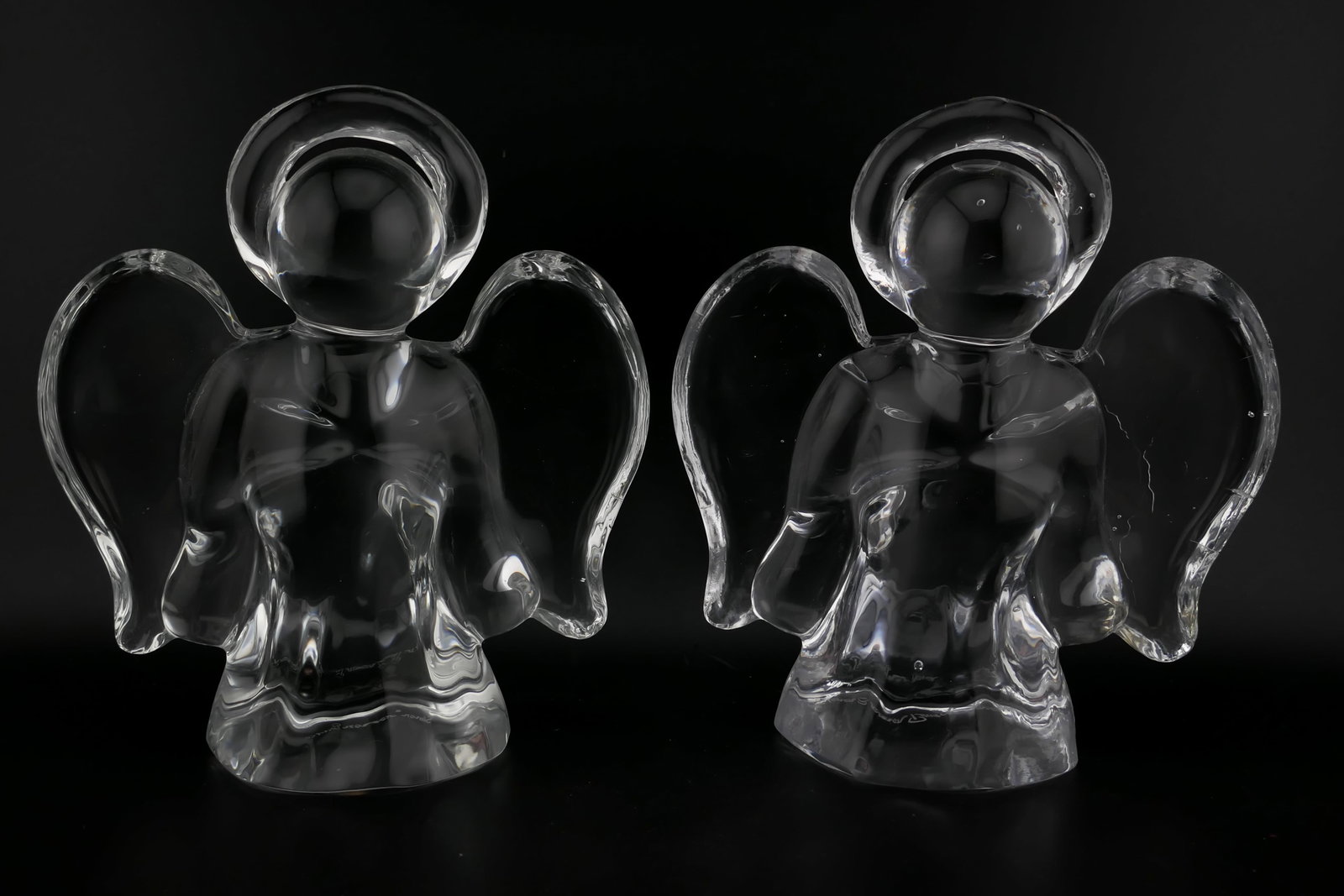 Simon Pearce Crystal Angel Pair: Pair of marked Simon Pearce crystal angel figurines. Both signed Simon Pearce on the bottom. Very good condition with an internal crack in one wing. Size: 3.75"w x 1.5"d x 4"h Location: Living Room
