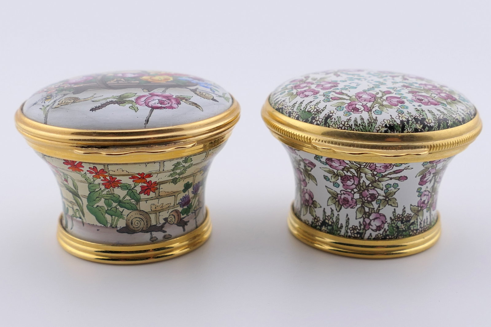 Halcyon Days Floral Trinket Box Pair: Pair of marked Halcyon Days hinged trinket boxes, both in dense floral motifs. One shows a quote on the inner lid. Both are marked on the bottom Halcyon Days Enamels. Very good condition with one lid 