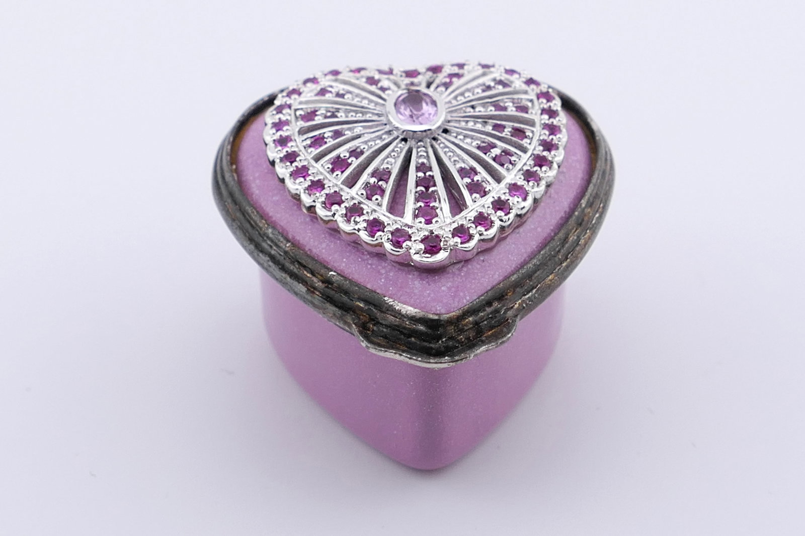 Halcyon Days Jeweled Trinket Box: Marked Halcyon Days hinged trinket box featuring a heart-shaped design with a lid accented with rhinestones inspired by a Faberge brooch. Marked on the bottom Halcyon Days Enamels. Excellent condition