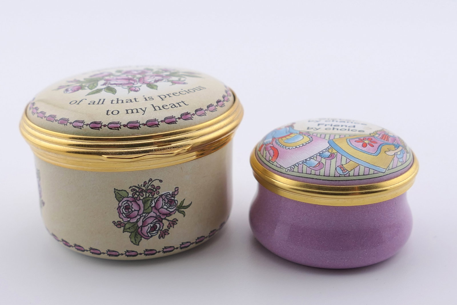 Two Halcyon Days Sister Trinket Boxes: Two marked Halcyon Days trinket boxes themed for sisters, one with a hinged lid, one with a twist lid. Both are marked on the bottom Halcyon Days Enamels. One is commissioned by the Horchow Collection