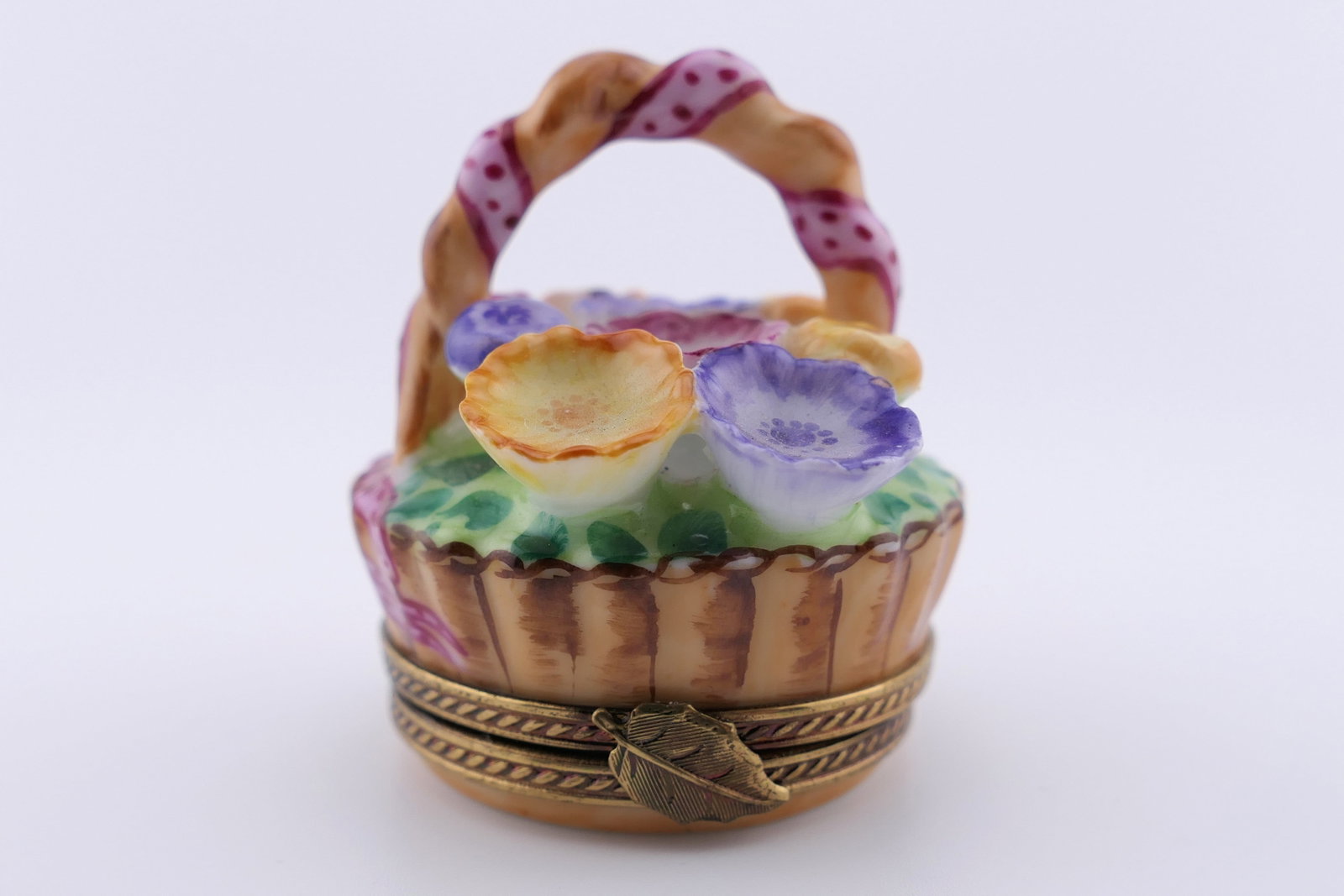 Limoges Porcelain Flower Basket Trinket Box: Marked Limoges hand painted porcelain hinged trinket box featuring a design of a small round basked of colorful flowers. Marked on the bottom Limoges France. Excellent condition. Size: 1.25"dia Locati