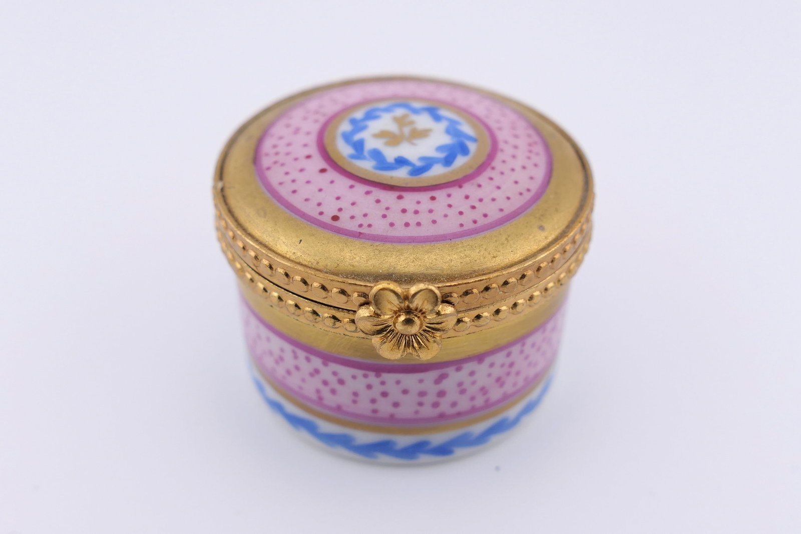 Limoges Porcelain Pink Pill Box: Marked Limoges hand painted porcelain hinged pill box featuring an overall pink design with floral motifs. Marked on the bottom Limoges France. Very good condition, with the lid latch slightly loose. 