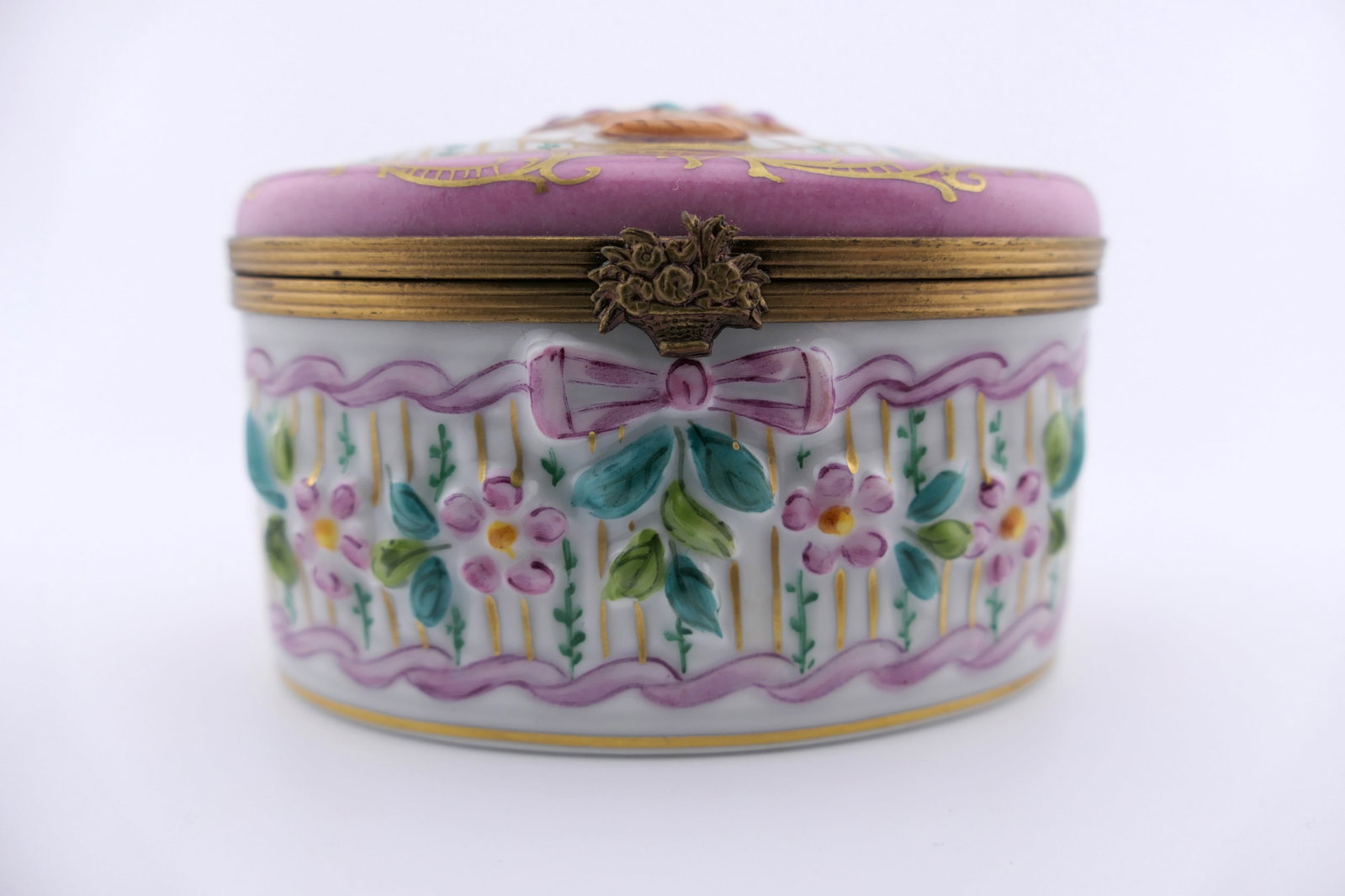 Limoges Porcelain Pink Trinket Box: Marked Limoges hand painted porcelain hinged trinket box featuring an overall pink oval design with floral motifs. Marked on the bottom Limoges France. Excellent condition. Size: 3"w x 2"d x 2"h Locat