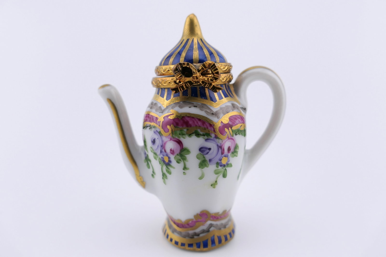 Limoges Porcelain Coffee Pot Trinket Box: Marked Limoges hand painted porcelain hinged trinket box featuring a design shaped as a coffee pot with floral motifs and gilt accenting. Marked on the bottom Limoges France. Excellent condition. Size