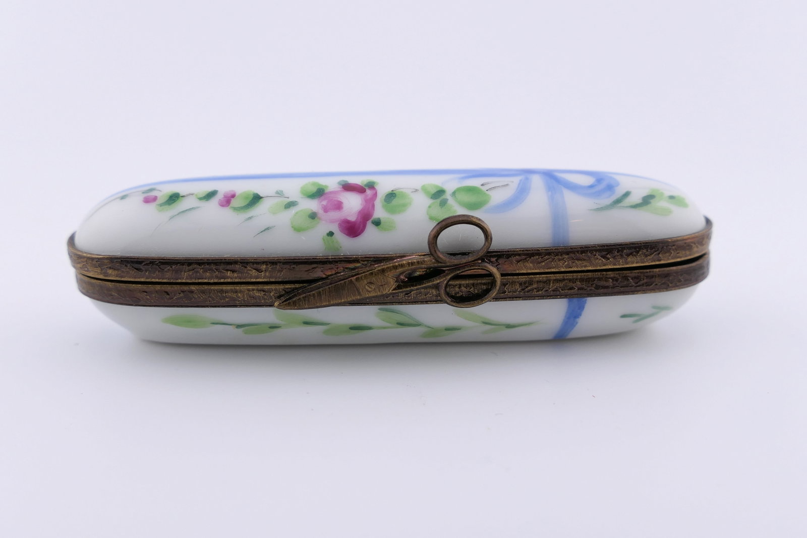 Limoges Porcelain Needle Case: Marked Limoges hand painted porcelain hinged needle case featuring a blue ribbon and floral motif. Marked on the bottom Limoges France. Excellent condition. Size: 3"w Location: Living Room