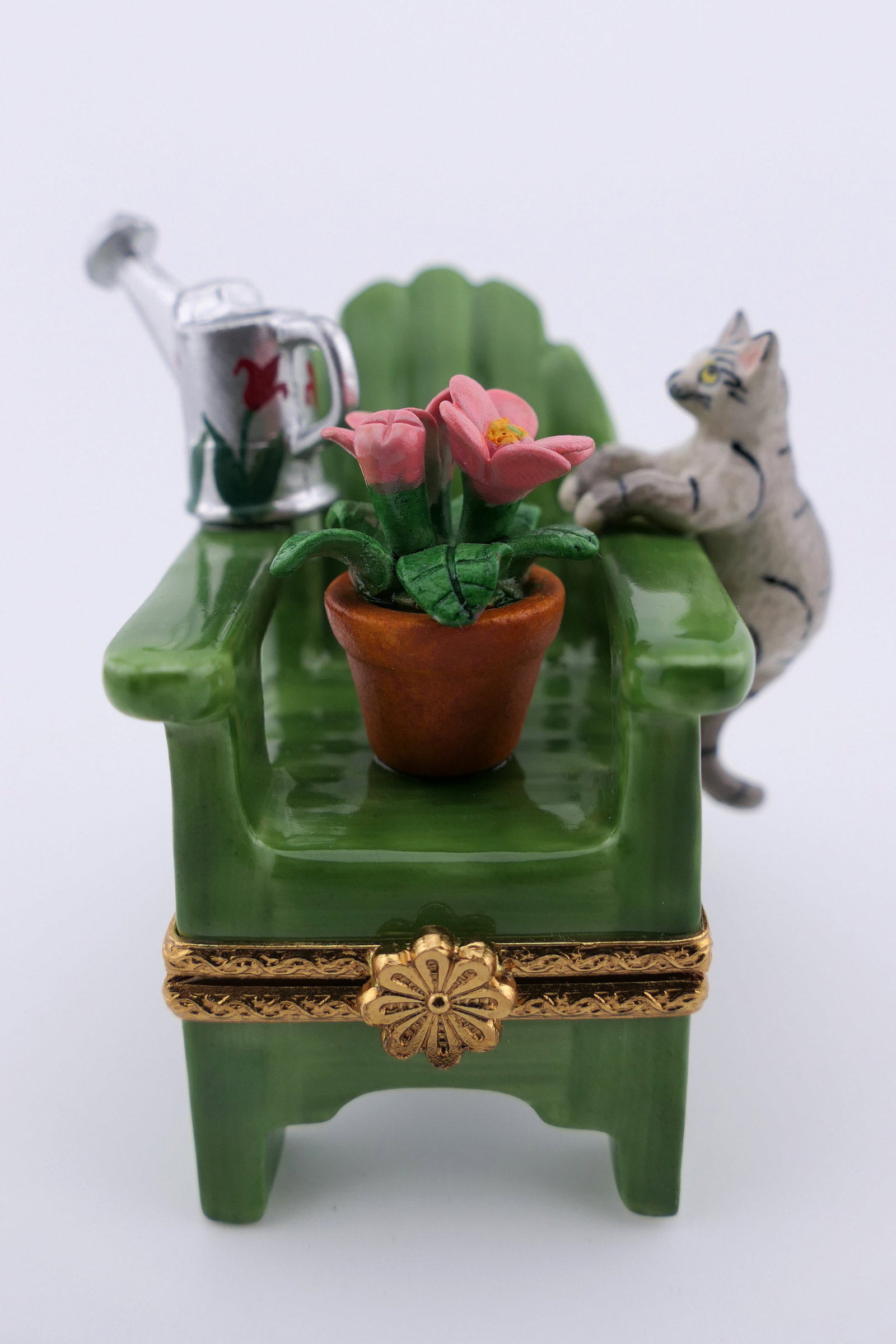 Limoges Porcelain Garden Chair Trinket Box: Limoges hand painted porcelain hinged trinket box featuring a design of a garden chair with a watering can and cat. Marked on the bottom Limoges France. Excellent condition. Size: 2.75"h Location: Liv
