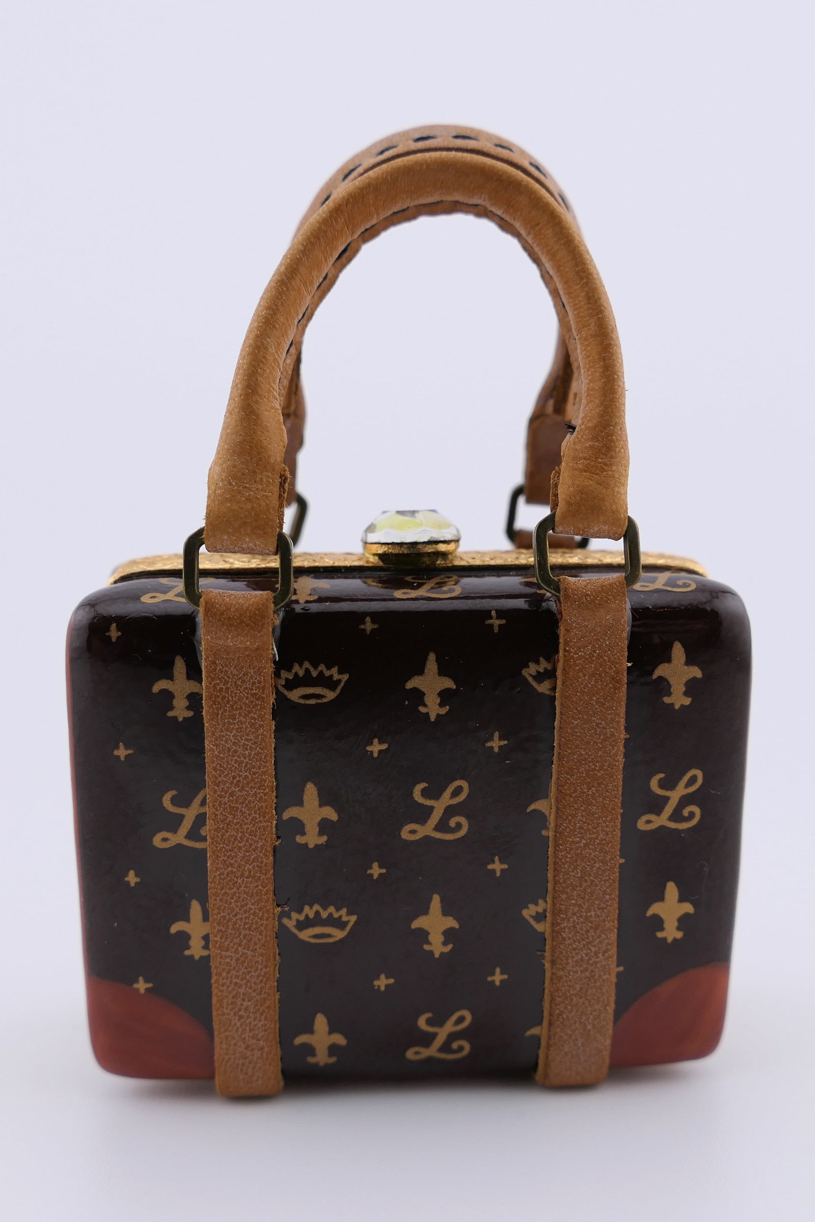 Limoges Porcelain Monogram Bag Trinket Box: Limoges hand painted porcelain hinged trinket box featuring a hand bag design with leather handles, in a style reminiscent of Louis Vuitton with a repeating monogram, and containing a miniature lipsti
