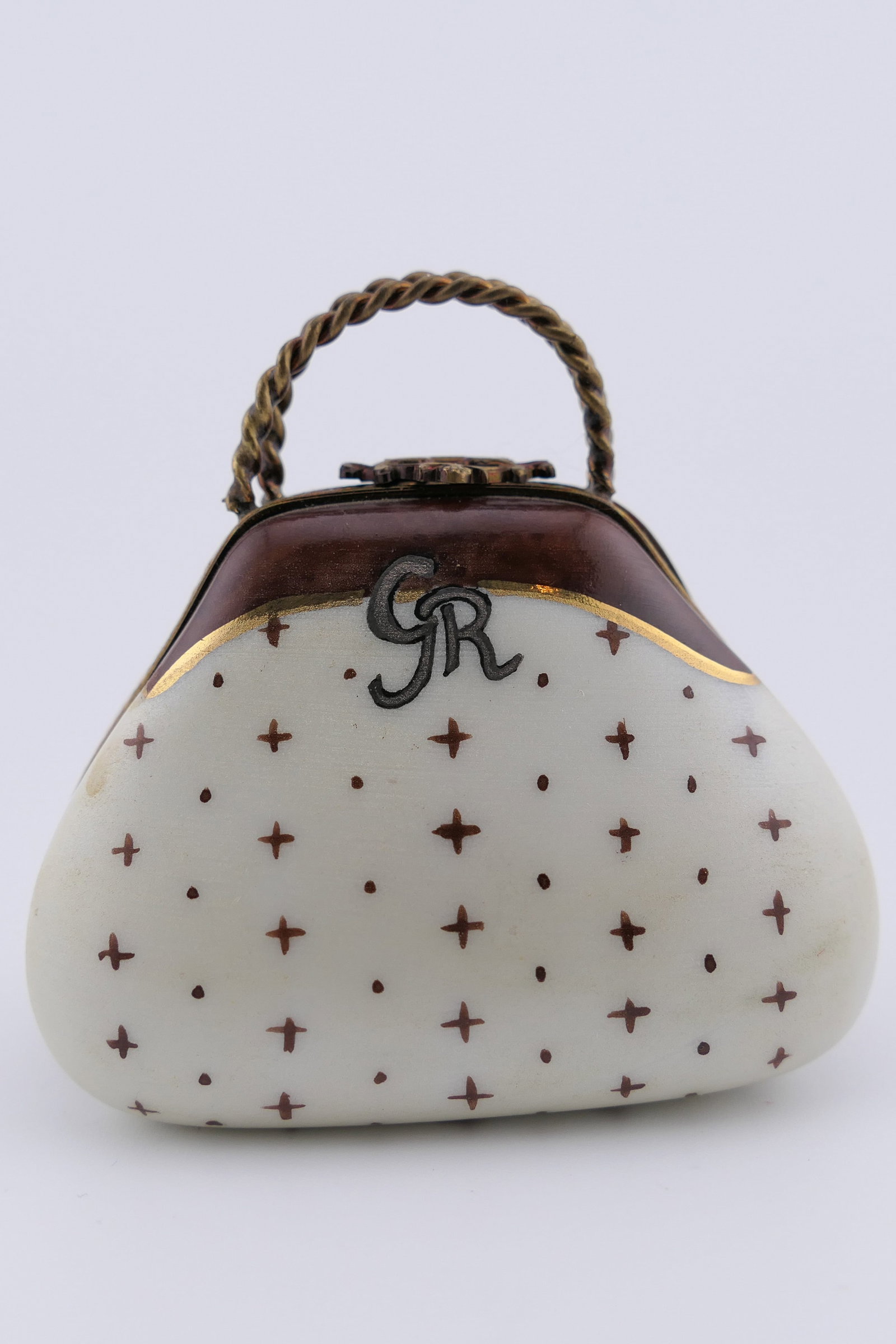 Limoges Porcelain Handbag Trinket Box: Limoges hand painted porcelain hinged trinket box featuring a hand bag design with metal handles and a repeating gilt star motif, containing miniature glasses. Marked on the inside Limoges France, Lim