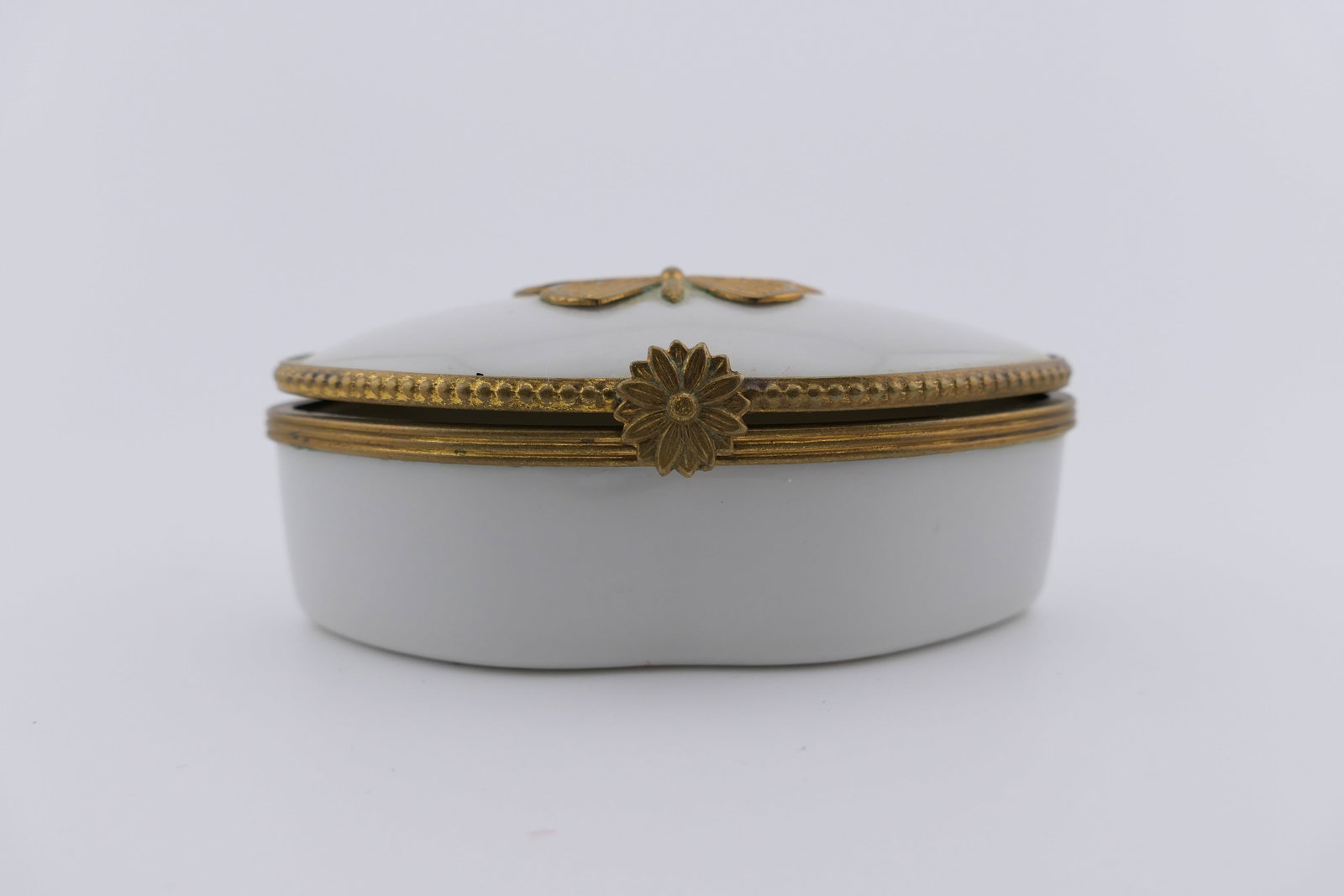 Limoges Porcelain Butterfly Trinket Box: Limoges hand painted porcelain hinged trinket box featuring an overall cream design with a gold tone metal butterfly on the lid. Marked on the bottom Limoges France. Very good condition, with a loose 