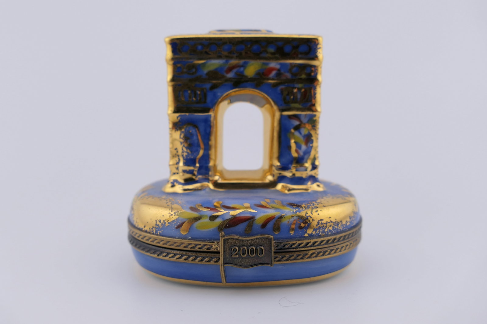 Limoges Porcelain New Millennium Trinket Box: Limoges hand painted porcelain hinged trinket box featuring a design of the Arc De Triumph in blue with gilt accenting. Marked inside Bonne Annee 2000 for the new year. Marked on the bottom Limoges Fr