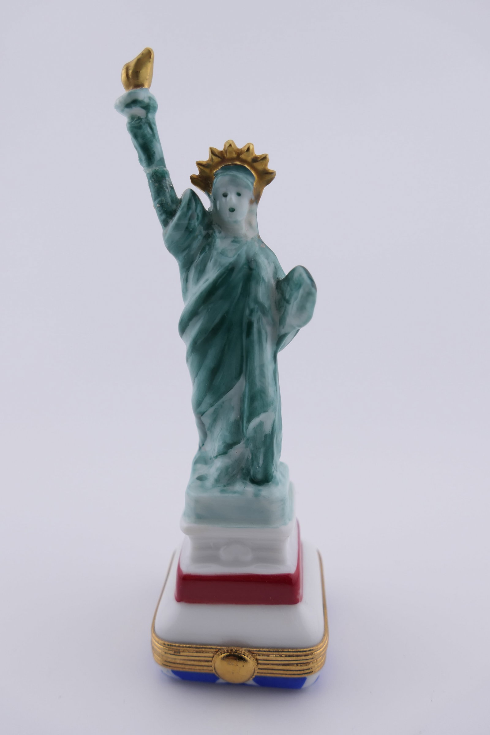 Limoges Porcelain Statue of Liberty Trinket Box: Limoges hand painted porcelain hinged trinket box featuring a design of the Statue of Liberty. Marked on the bottom Pierre Arquie, Limoges France. Good condition, showing a repaired arm. Size: 4.5"h L